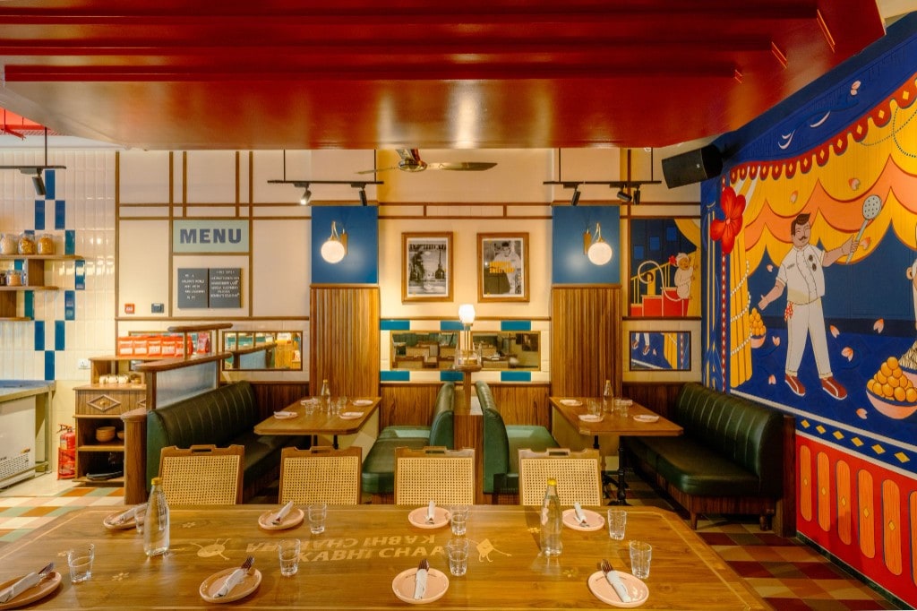 Communal table, green booths, and chef mural under red ceiling