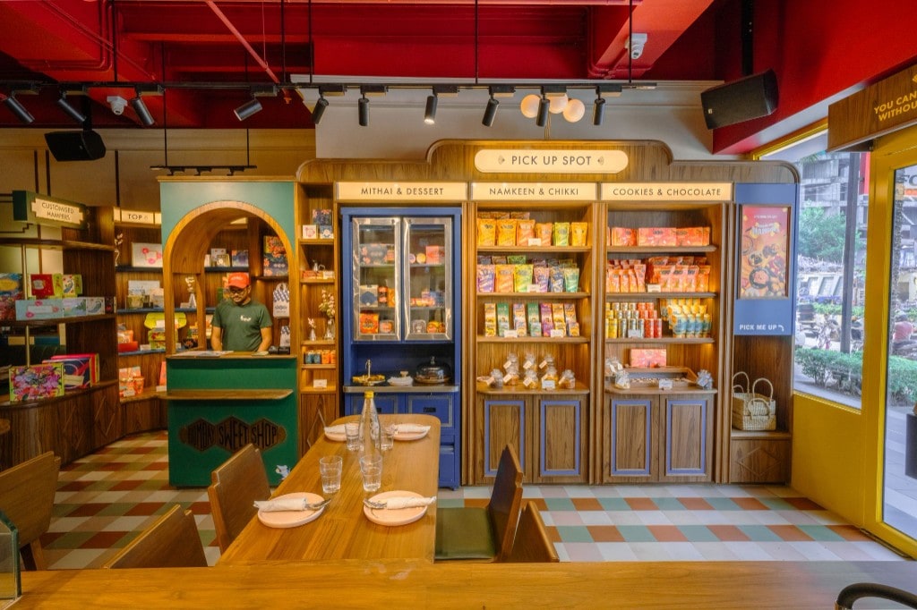 Pick-up wall, product shelving, and dining table toward yellow entrance